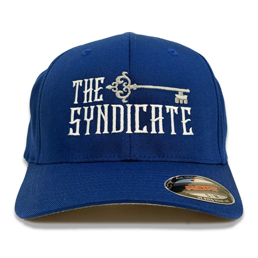 A blue FlexFit hat with 'THE SYNDICATE' text and a key logo embroidered on the front.